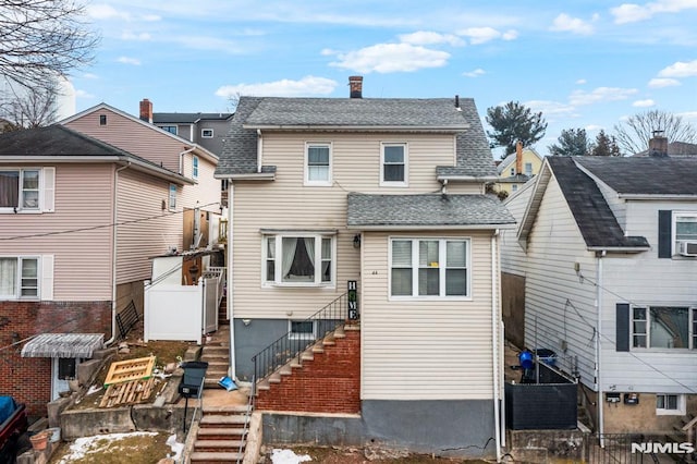 back of house featuring a shingled roof and stairs