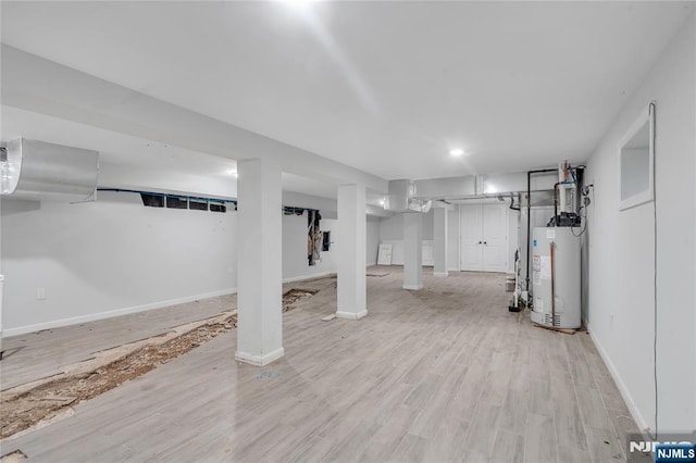 basement featuring light hardwood / wood-style floors and gas water heater