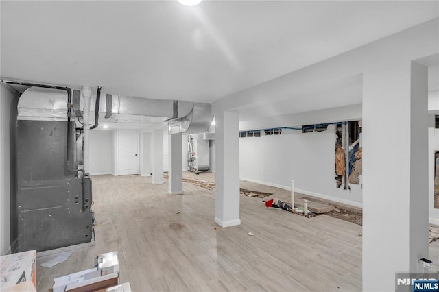 basement with heating unit and light hardwood / wood-style flooring