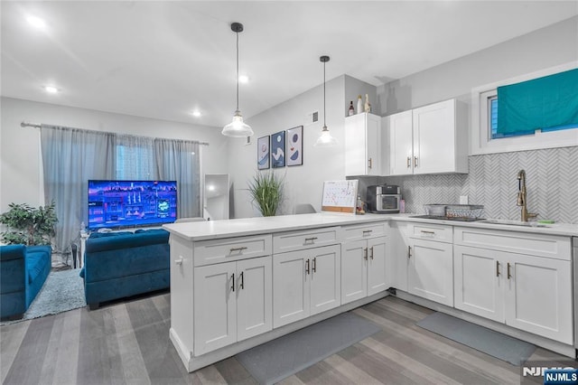 kitchen featuring tasteful backsplash, white cabinets, decorative light fixtures, sink, and kitchen peninsula