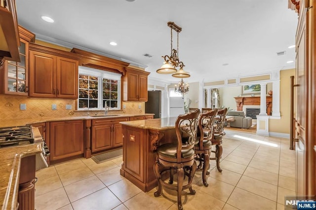 kitchen with sink, crown molding, pendant lighting, and light tile patterned floors