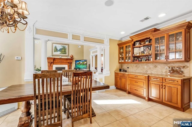 dining area with light tile patterned flooring, crown molding, and ornate columns