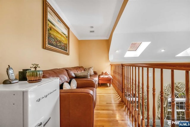 interior space with a skylight, crown molding, and light hardwood / wood-style floors