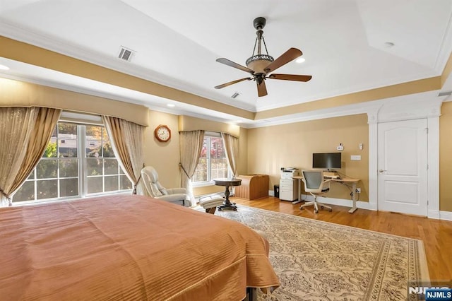 bedroom with ceiling fan, ornamental molding, a raised ceiling, and hardwood / wood-style floors