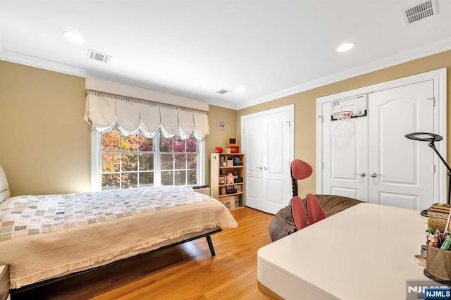 bedroom featuring ornamental molding, multiple closets, and hardwood / wood-style floors