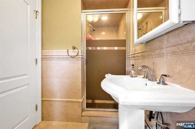 bathroom with sink, tile walls, and a shower with door