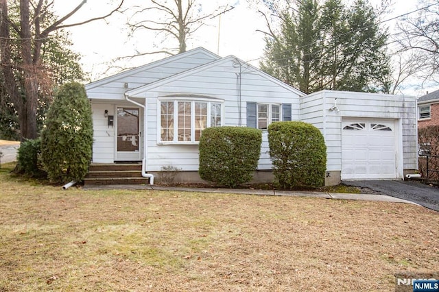 view of front facade with entry steps, aphalt driveway, a garage, and a front lawn