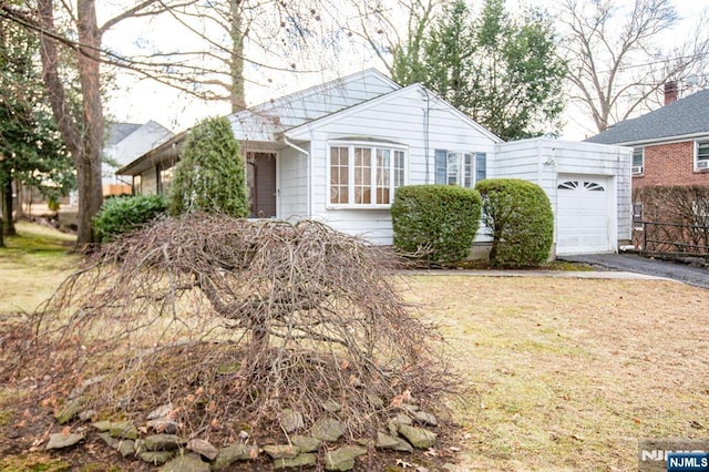 view of front facade featuring a garage, a front yard, and driveway