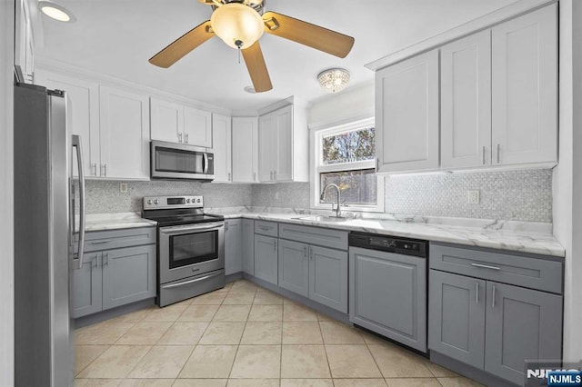 kitchen featuring light tile patterned floors, gray cabinetry, a sink, appliances with stainless steel finishes, and tasteful backsplash