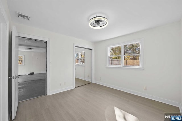 unfurnished bedroom with light wood-type flooring, baseboards, and visible vents