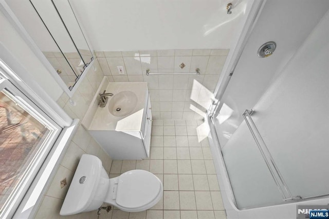 bathroom with toilet, vanity, and tile walls