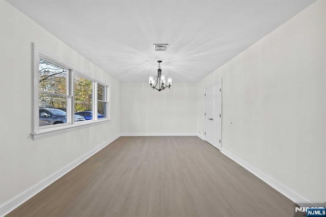 unfurnished dining area with an inviting chandelier, baseboards, visible vents, and dark wood finished floors