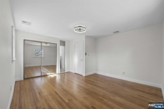 unfurnished bedroom featuring visible vents, baseboards, and wood finished floors