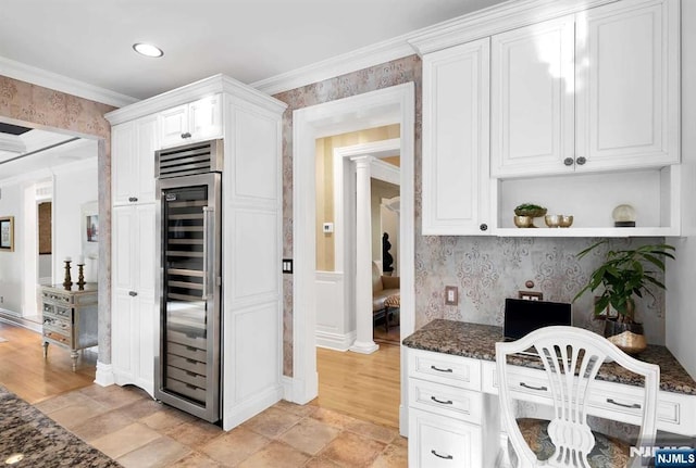 kitchen with beverage cooler, dark stone counters, and white cabinets