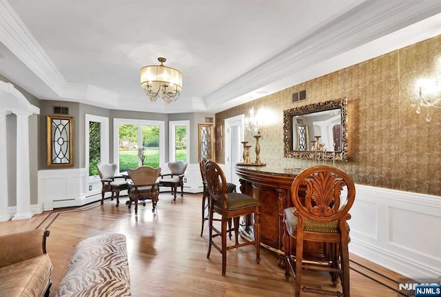 dining space with visible vents, a baseboard heating unit, wainscoting, a chandelier, and ornate columns