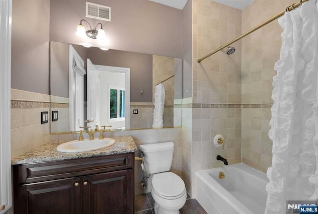 full bath featuring toilet, vanity, visible vents, tile walls, and shower / bath combination with curtain