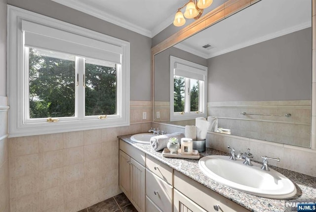 full bath with crown molding, a wainscoted wall, a sink, and double vanity