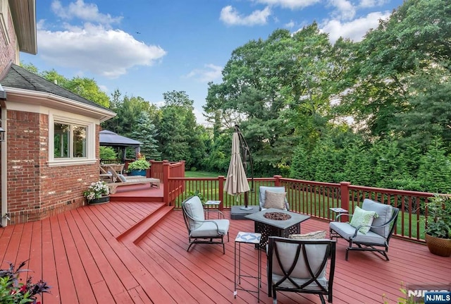 wooden terrace with a fire pit and a gazebo