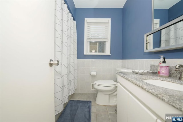 bathroom with vanity, tile patterned flooring, tile walls, and toilet