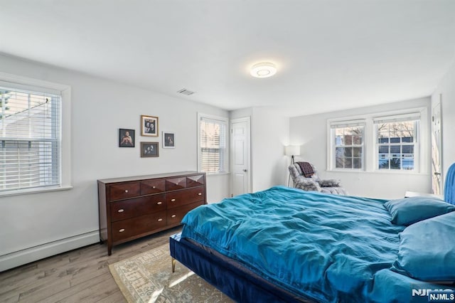 bedroom featuring light wood finished floors, visible vents, a baseboard radiator, and multiple windows