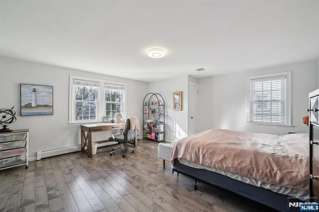 bedroom with visible vents, wood finished floors, multiple windows, and baseboards