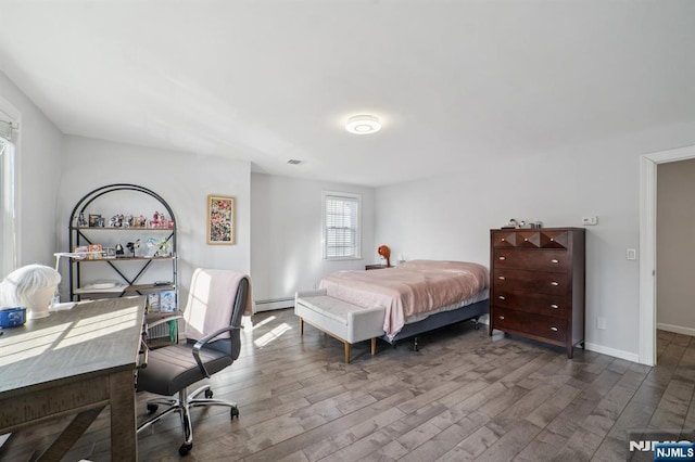 bedroom with a baseboard radiator, baseboards, wood finished floors, and visible vents