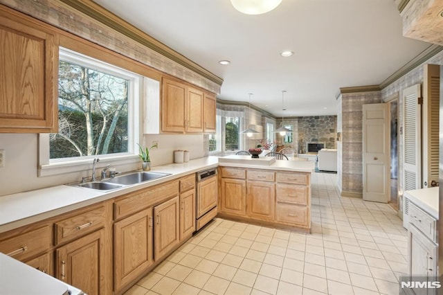 kitchen featuring a peninsula, ornamental molding, light countertops, and a sink