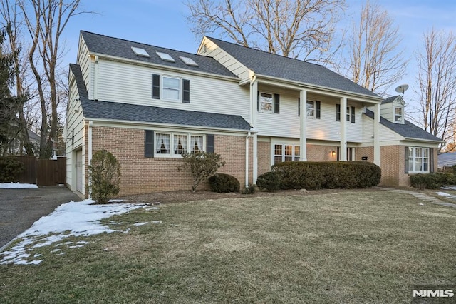 view of front of home featuring a shingled roof, a garage, brick siding, and a front lawn