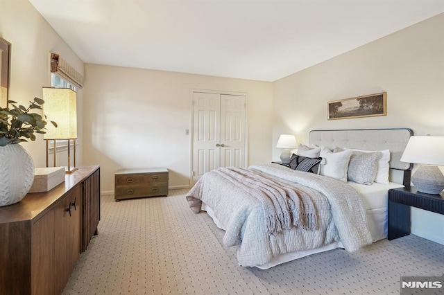 bedroom with light carpet, baseboards, and a closet