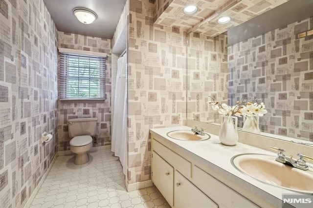 full bath with toilet, a shower with curtain, double vanity, and a sink