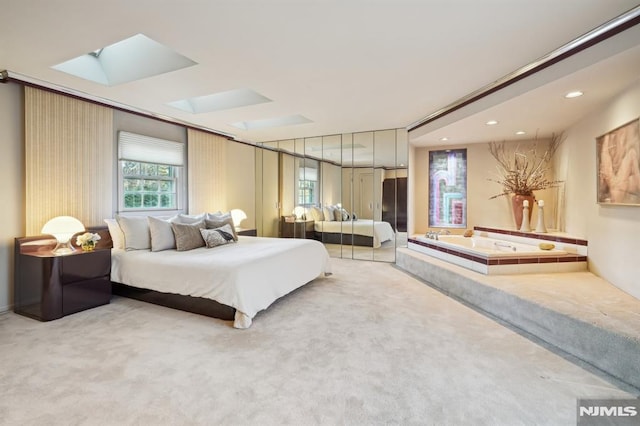 bedroom featuring light carpet, a skylight, and recessed lighting