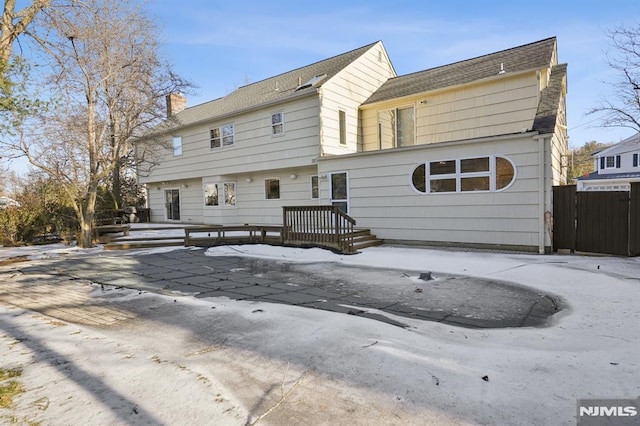 exterior space with a chimney, fence, and a deck