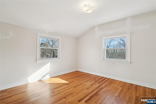 additional living space with a wealth of natural light, vaulted ceiling, baseboards, and wood finished floors