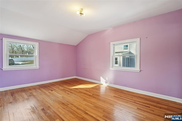 bonus room featuring light wood-type flooring, a wealth of natural light, lofted ceiling, and baseboards