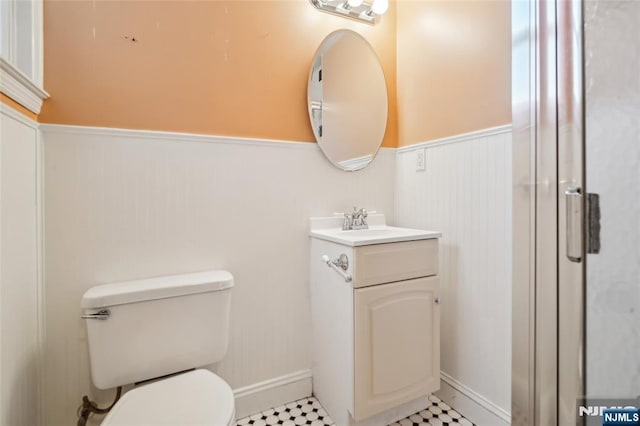 bathroom featuring toilet, a wainscoted wall, and vanity