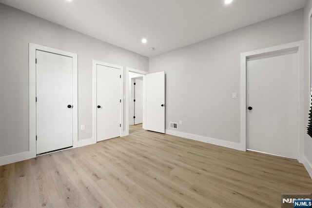 unfurnished bedroom featuring recessed lighting, visible vents, baseboards, multiple closets, and light wood-style floors