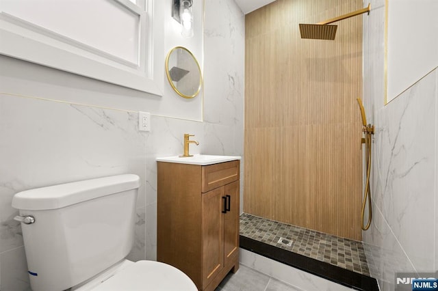 bathroom featuring a walk in shower, vanity, toilet, and tile walls