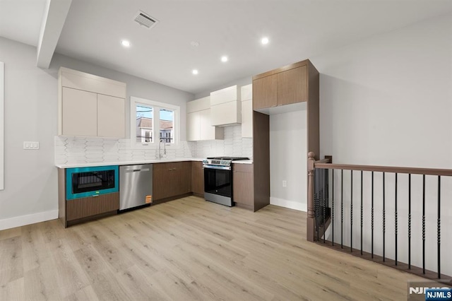 kitchen featuring stainless steel appliances, visible vents, light countertops, decorative backsplash, and modern cabinets