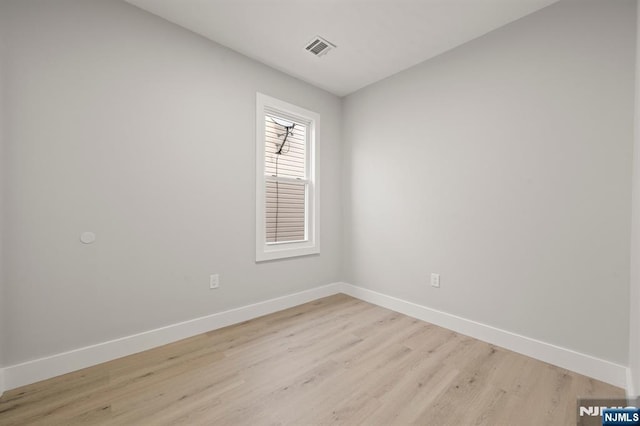 empty room featuring light wood finished floors, visible vents, and baseboards