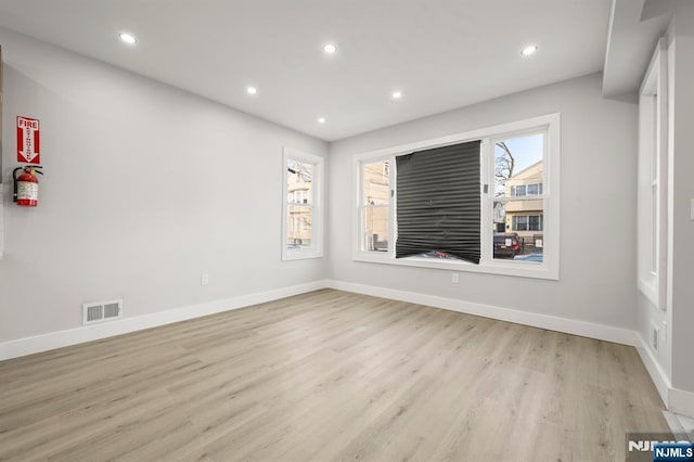 empty room featuring baseboards, light wood finished floors, visible vents, and recessed lighting