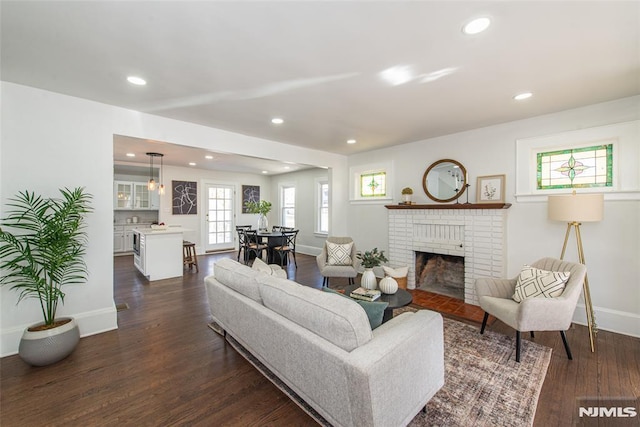 living area featuring baseboards, a fireplace, recessed lighting, and dark wood-style flooring