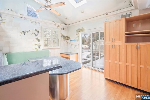 kitchen with light wood-style floors, vaulted ceiling with skylight, a healthy amount of sunlight, and open shelves