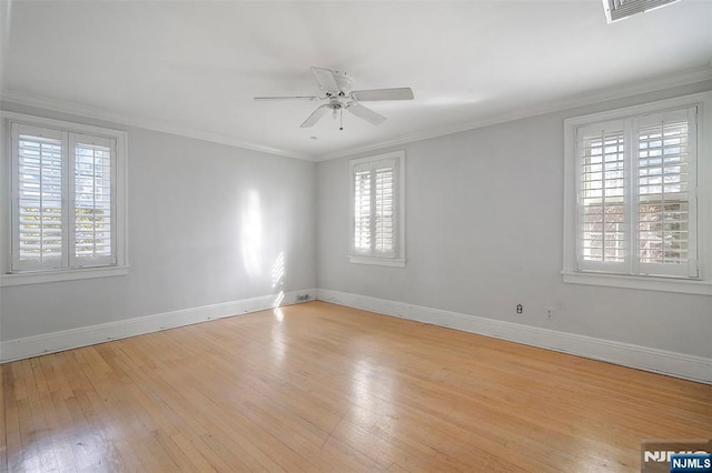 spare room featuring ornamental molding, visible vents, light wood-style flooring, and baseboards