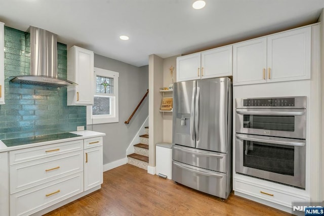 kitchen featuring appliances with stainless steel finishes, light countertops, white cabinets, and wall chimney exhaust hood