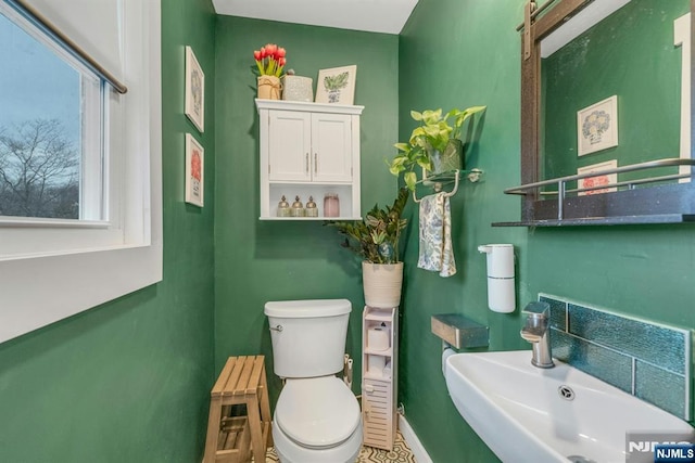 half bath with a sink, toilet, and baseboards