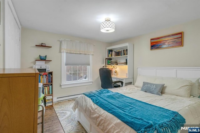 bedroom with light wood-style flooring and a baseboard heating unit