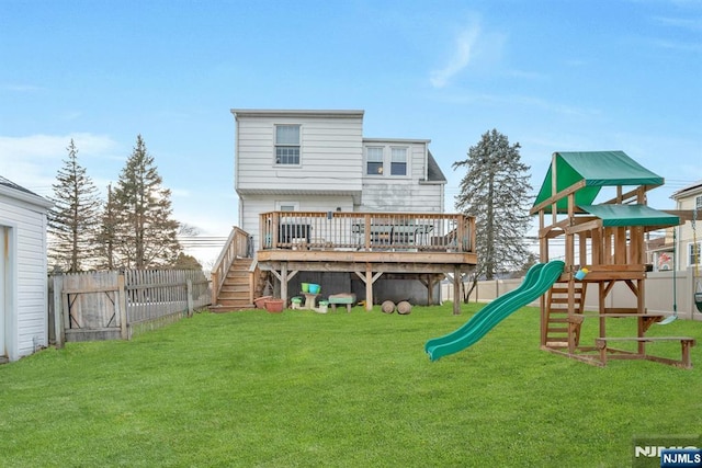 rear view of property with a lawn, a playground, fence, and a wooden deck