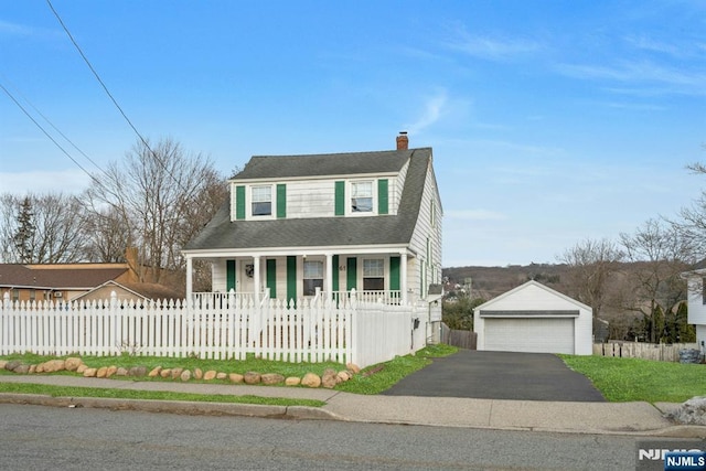 view of front of house featuring a porch, a fenced front yard, a garage, an outdoor structure, and a chimney