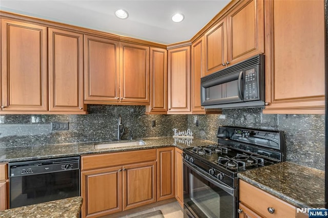 kitchen with a sink, backsplash, dark stone counters, black appliances, and brown cabinetry