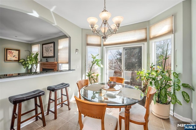 dining area with light tile patterned floors, baseboards, arched walkways, ornamental molding, and an inviting chandelier